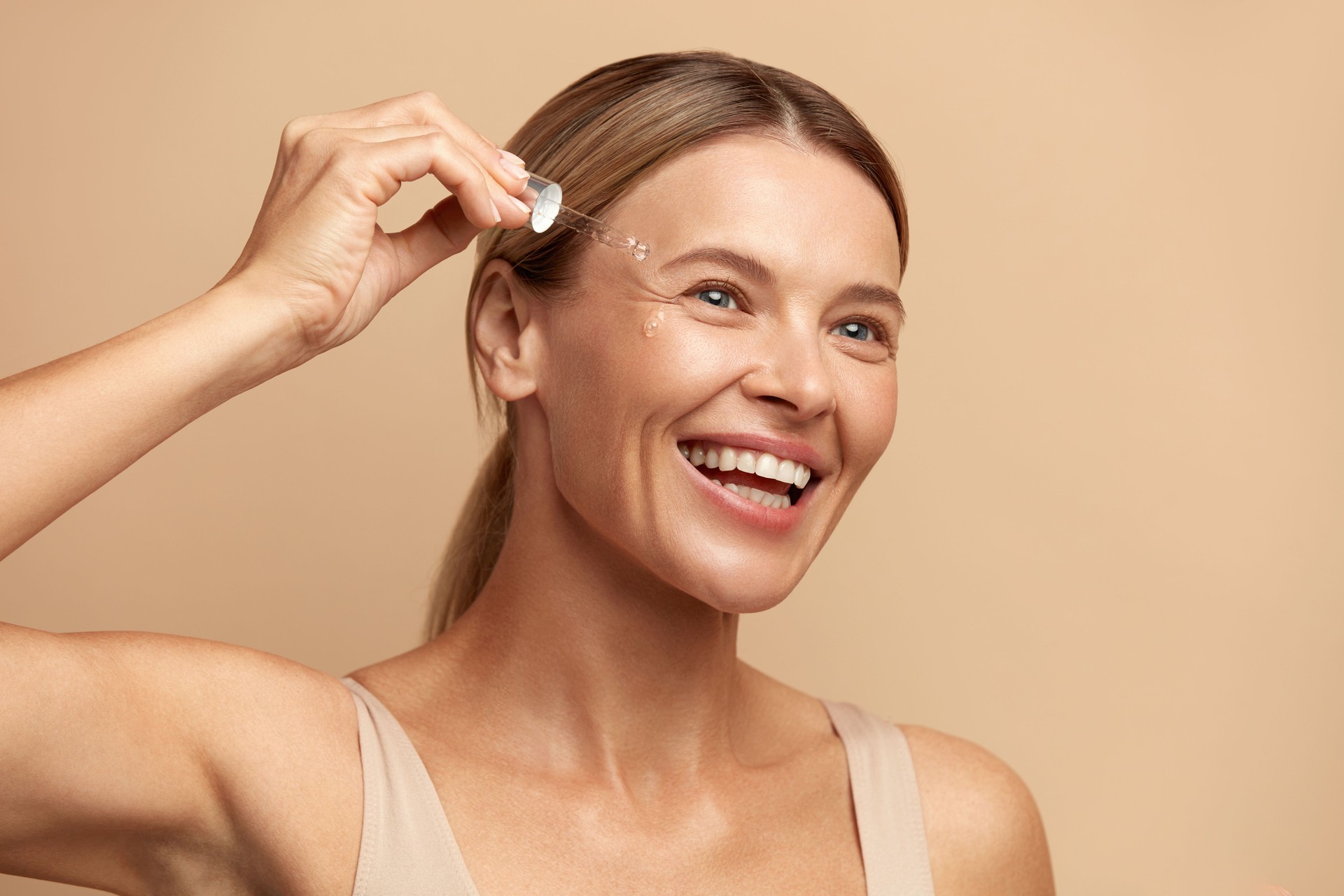 Skin Care. Beauty Portrait Of Woman Dropping Serum Collagen Moisturiser on Face